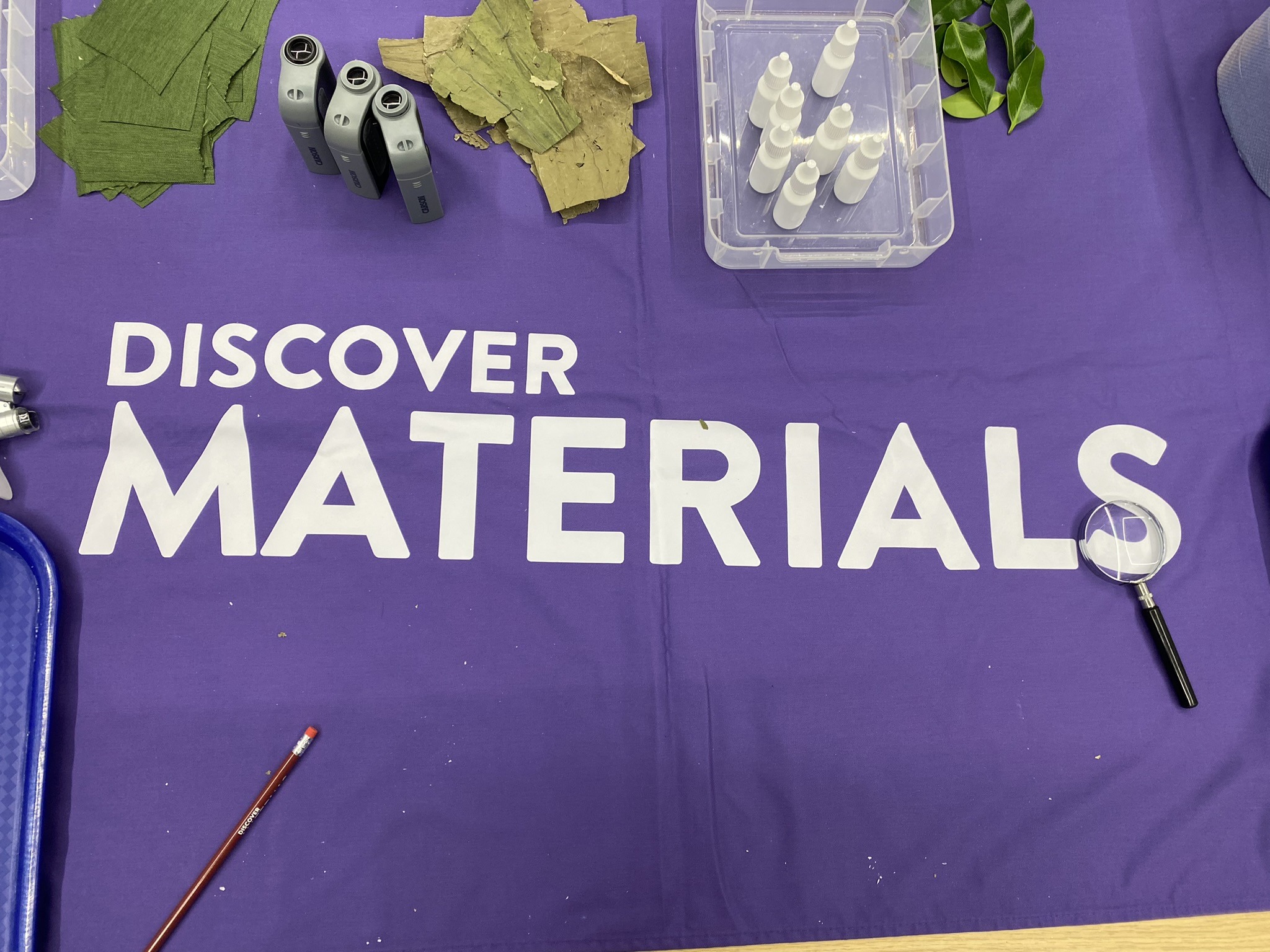 Discover Materials Logo printed on a tablecloth with a range of outreach materials.